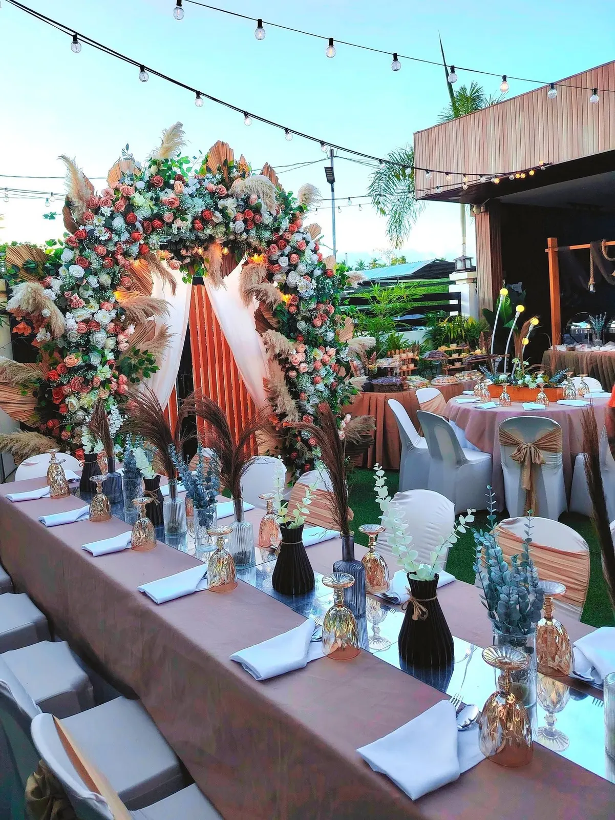 Long garden table set for a celebration on the villa lawn under string lights