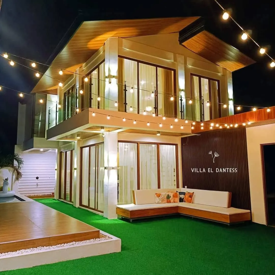 The villa at night: string lights over the lawn and the lit Villa El Dantess sign