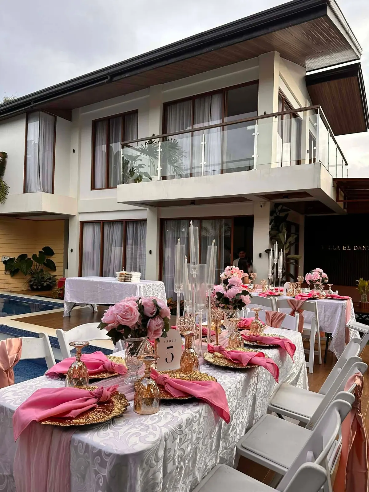 Pink and white tables across the lawn in front of the villa